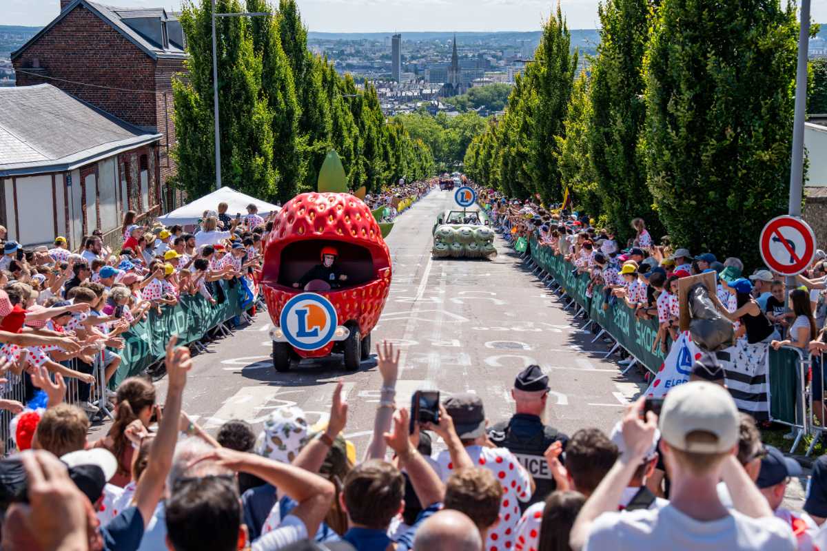 Chars Fraise et Poireau de la caravane E.Leclerc défilant en ville, entourés d’une foule enthousiaste de spectateurs et de photographes.