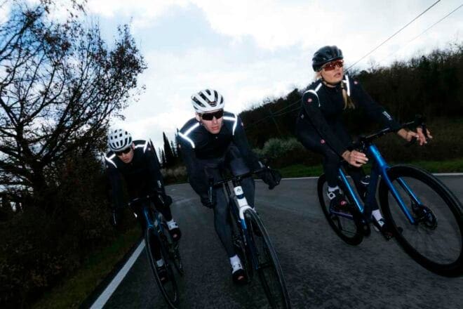 Cyclistes roulant en hiver vêtus de la veste Castelli Alpha 150, sur une route froide et dégagée, illustrant la protection et la respirabilité de la veste