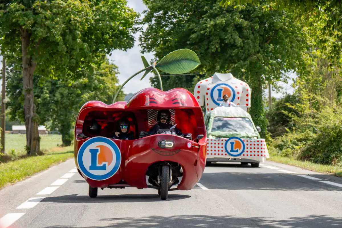Caravane E.Leclerc sur le Tour de France avec les chars Cerise et Maillot à Pois défilant sur les routes devant le public.