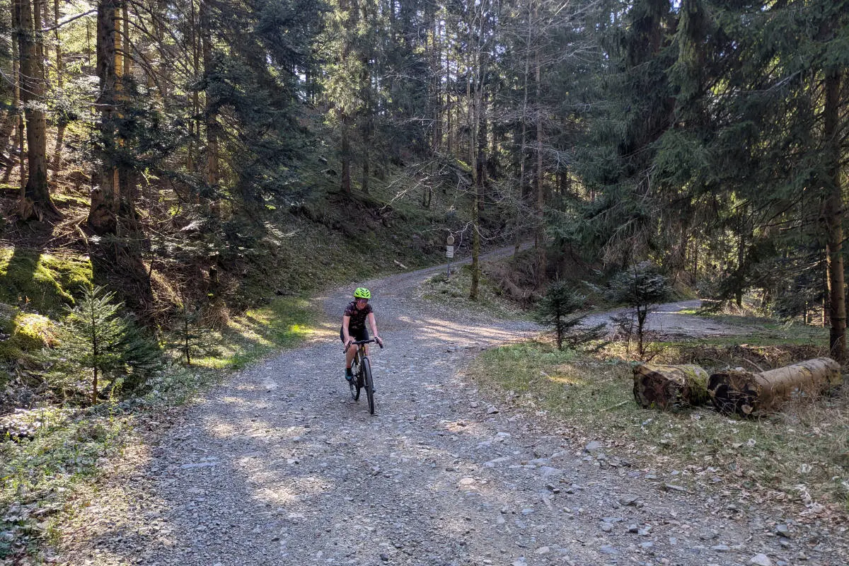 Femme cycliste grimpant une montée avec des graviers à vélo